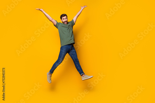 Full size photo of handsome young guy jump raise hands dressed stylish khaki outfit isolated on yellow color background