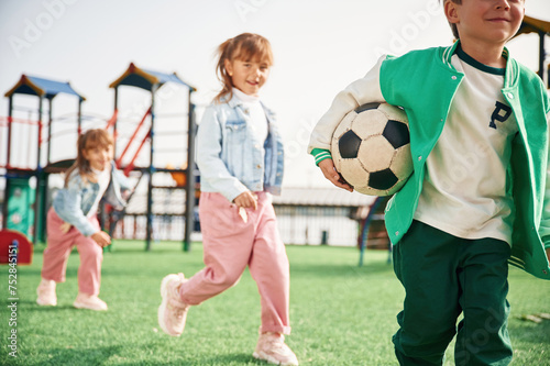 Fototapeta Naklejka Na Ścianę i Meble -  Holding soccer ball in hand, running. Kids are having fun on the playground