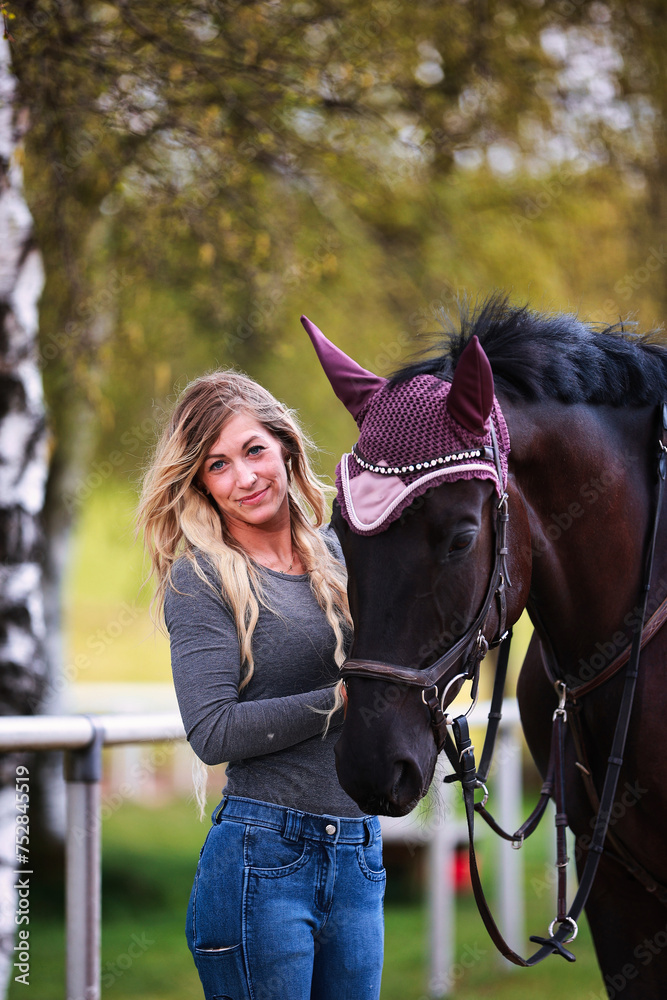 Obraz premium Young woman with long hair and blonde streaks, stands portraits with her horse.