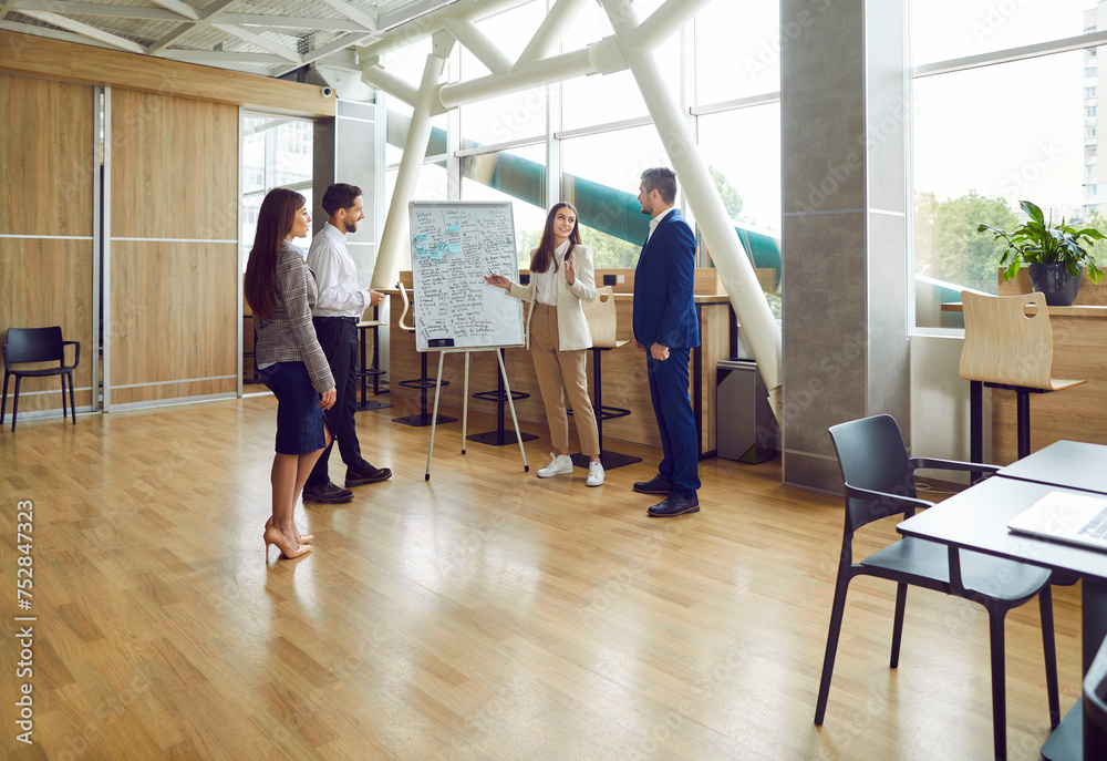 Group of business people talking on a meeting standing in circle in office. Company employees discussing work project. Coworkers listen to their colleague. Corporate business team concept.