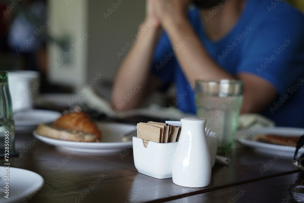A person is enjoying the hotel breakfast and eating at the restaurant. An adult is eating breakfast on a wooden nice table with glasses and croissant bread A person is enjoying the hotel breakfast and eating at the restaurant. An adult is eating breakfast on a wooden nice table with glasses and croissant bread
