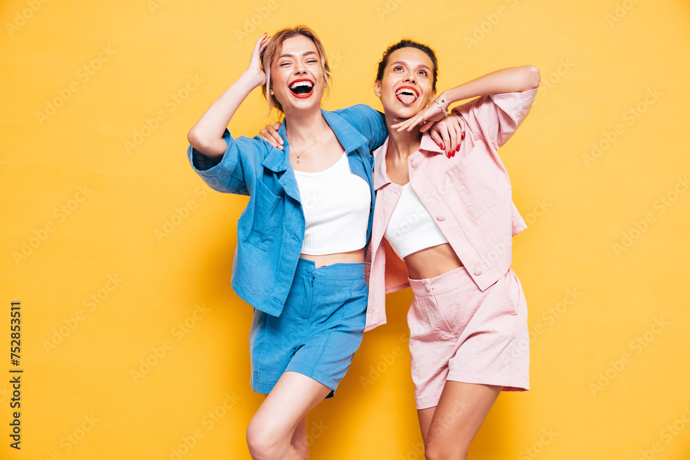 Two young beautiful smiling brunette hipster female in trendy summer clothes. Sexy carefree women posing in studio. Positive models having fun. Cheerful and happy - obrazy, fototapety, plakaty 