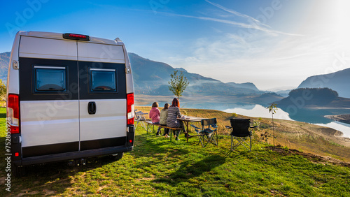 Campervan, Motorhome RV parked next to the lake or river in Bosnia and Herzegovina. Family with camper van or motor home eating breakfast on an active family vacation on a road trip to Ramsko lake.