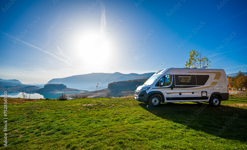 Fototapeta premium Campervan, Motorhome RV parked next&nbsp;to the lake or river in Bosnia and Herzegovina. Travelers with camper&nbsp;van&nbsp;or motor&nbsp;home are resting on an active family vacation on a road trip to Ramsko lake.&nbsp;&nbsp;