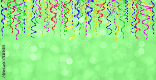 Falling confetti and curly colorful shiny streamer on green blurred background. Empty space for text