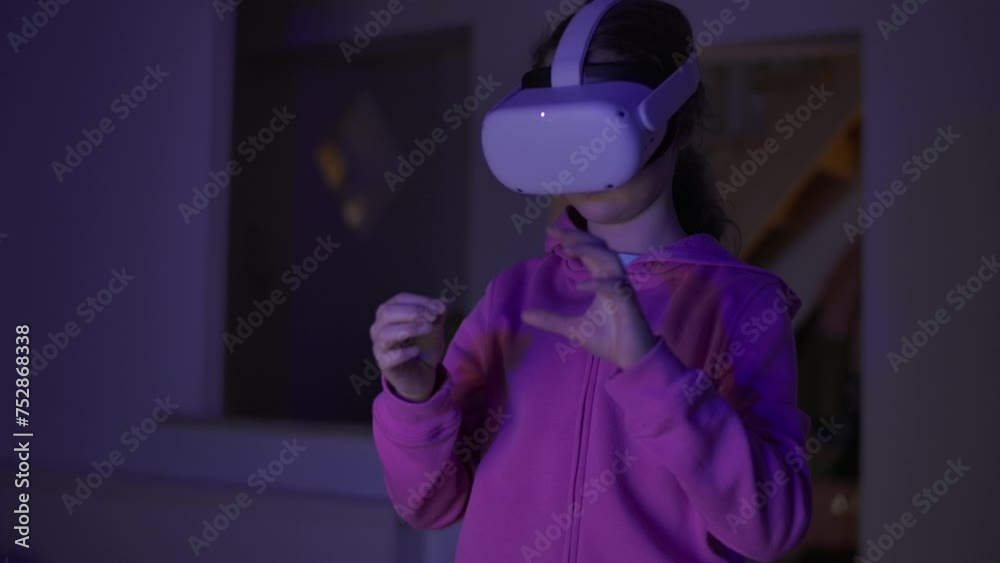 Girl Wearing Pink Hoodie is Playing Video Game With Virtual Reality Headset. Child is Fully Immersed in Game and Enjoying Herself. Person Using Virtual Reality Headset Interactive Technology. Girl Wearing Pink Hoodie is Playing Video Game With Virtual Reality Headset. Child is Fully Immersed in Game and Enjoying Herself. Person Using Virtual Reality Headset Interactive Technology.