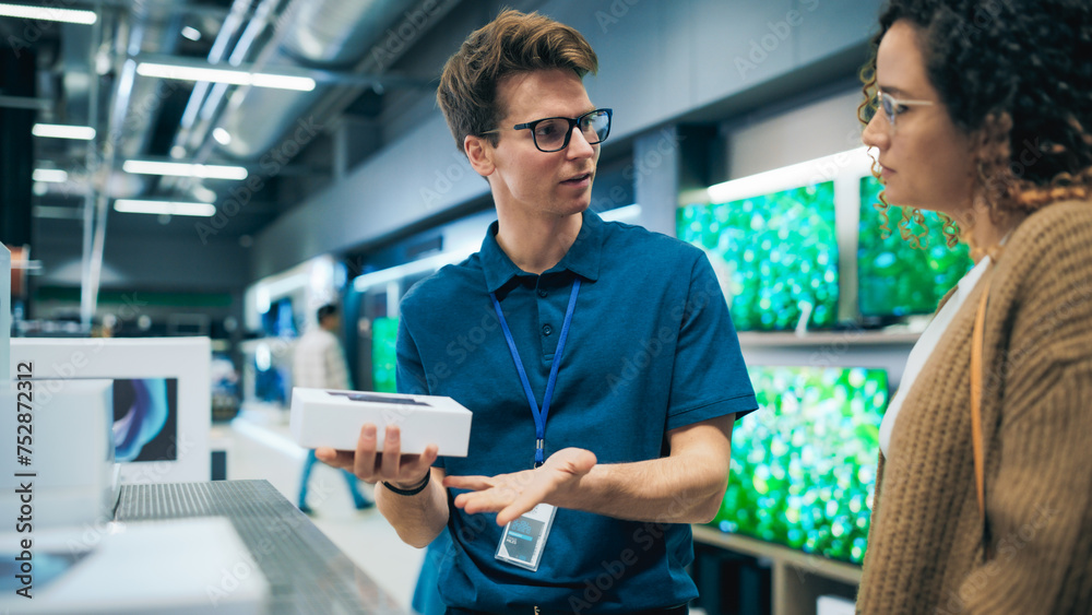 Obraz premium Portrait of Female Customer Seeking Advice from Retail Home Electronics Expert. Hispanic Girl Explores Smartphone Options. Shopper Evaluating Latest Mobile Phone Innovations in a Department Store