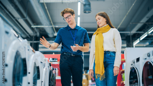 Portrait of a Retail Electronics Shop Consultant Assisting Young Female Customer in Selecting a Washing Machine. Beautiful Female Evaluating Modern Laundry Solutions