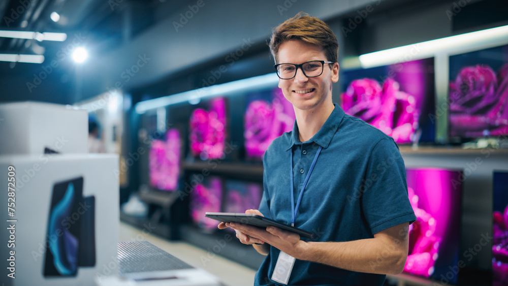Fototapeta premium Portrait of an Organized Handsome Assistant in Home Electronics Store Optimizing Workflows with Tablet Computer. Young Happy Team Member Looking at Camera and Smiling