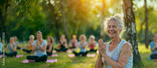 femme âgée qui fait un cours collectif de yoga dans un parle ensoleillé  photo