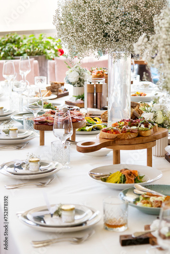 Served wedding table with decorative fresh white gypsophila flowers. Celebration details. Flower composition in plates. Serving food. Wedding decorations