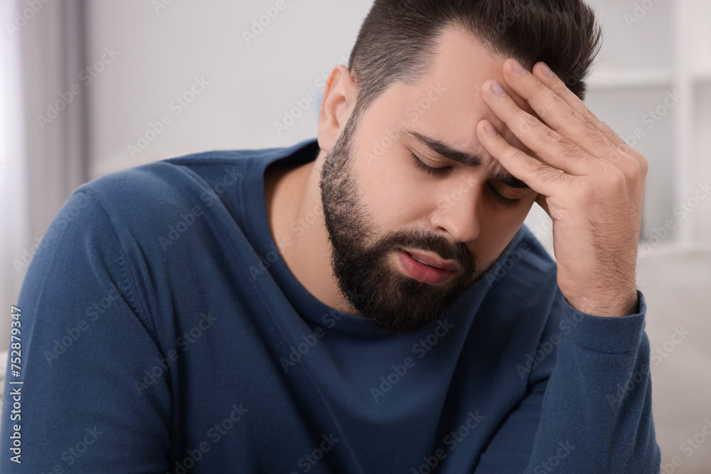 Unhappy man suffering from headache at home Unhappy man suffering from headache at home