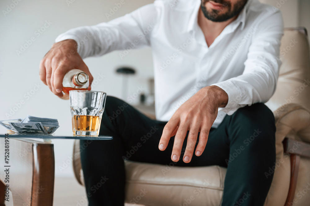 Pouring the whiskey into the glass. Upset young man drinker alcoholic is indoors Pouring the whiskey into the glass. Upset young man drinker alcoholic is indoors
