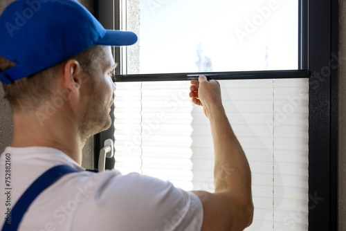 Φωτογραφία worker installing pleated blinds on the window