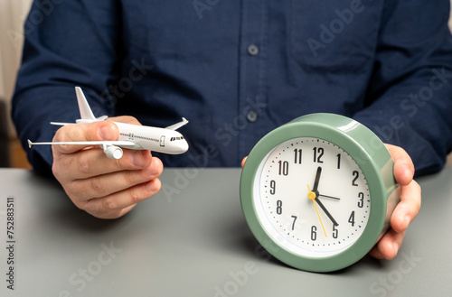 Fotografie A man holds a passenger plane and a clock