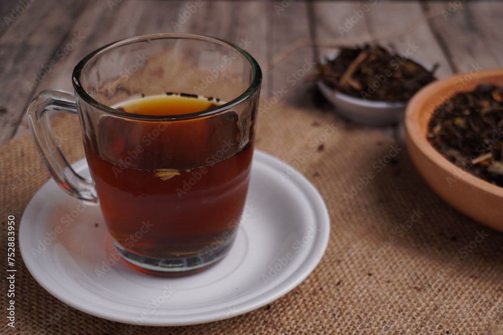 cup of black tea with saucer as base and dried tea leaves on side as ornament cup of black tea with saucer as base and dried tea leaves on side as ornament
