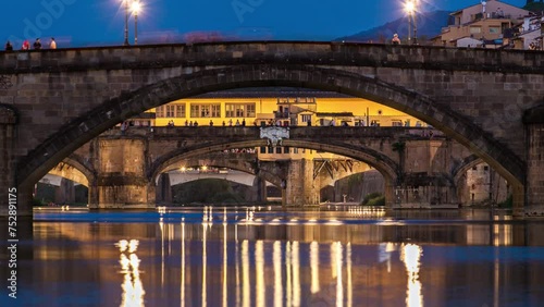 Twilight scene of Ponte Alla Carraia and Santa Trinita (Holy Trinity Bridge) day to night transition timelapse over River Arno with reflections on water after sunset. Florence, Tuscany, Italy photo