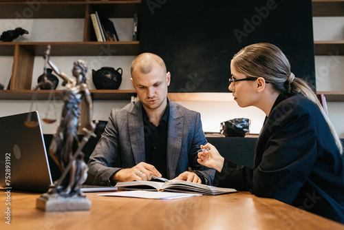 A lawyer meets with a new client. A young male lawyer in a suit sits at an office desk, shares legal advice, explains the inheritance process, tries to help. Legal advice concept