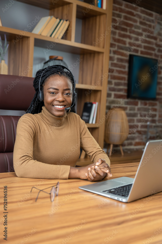 Woman with dreadlocks in headphones uses laptop for virtual teaching sessions Woman with dreadlocks in headphones uses laptop for virtual teaching sessions
