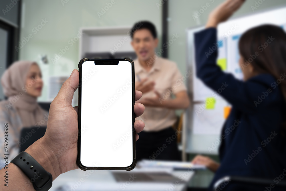 Business - technology and office concept - Hand holding mobile phone with blank screen in office.