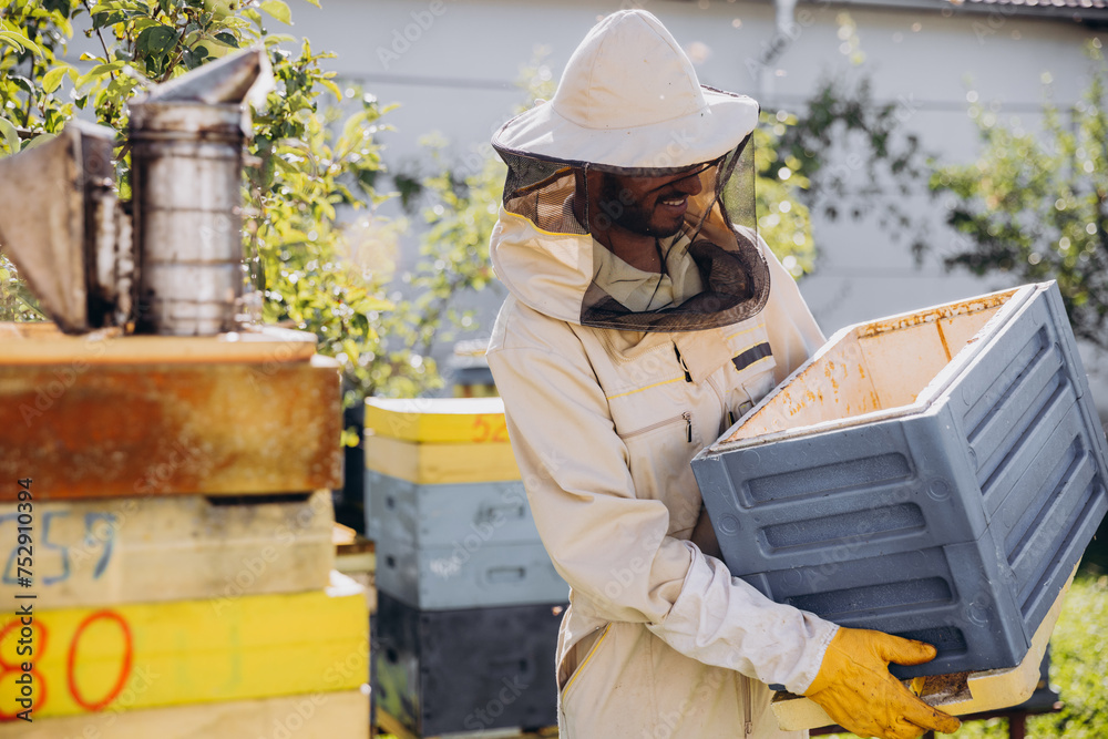 Beekeeper moves a beehive in the garden on a bee farm, beekeeping concept