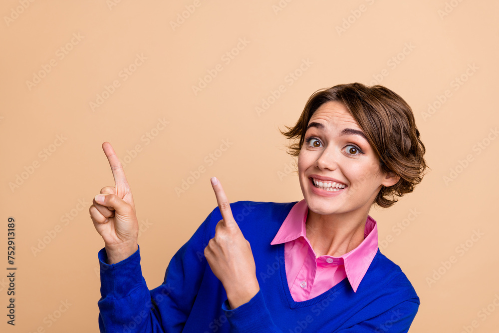 Photo portrait of lovely young lady point excited empty space promo dressed stylish blue garment isolated on beige color background Photo portrait of lovely young lady point excited empty space promo dressed stylish blue garment isolated on beige color background