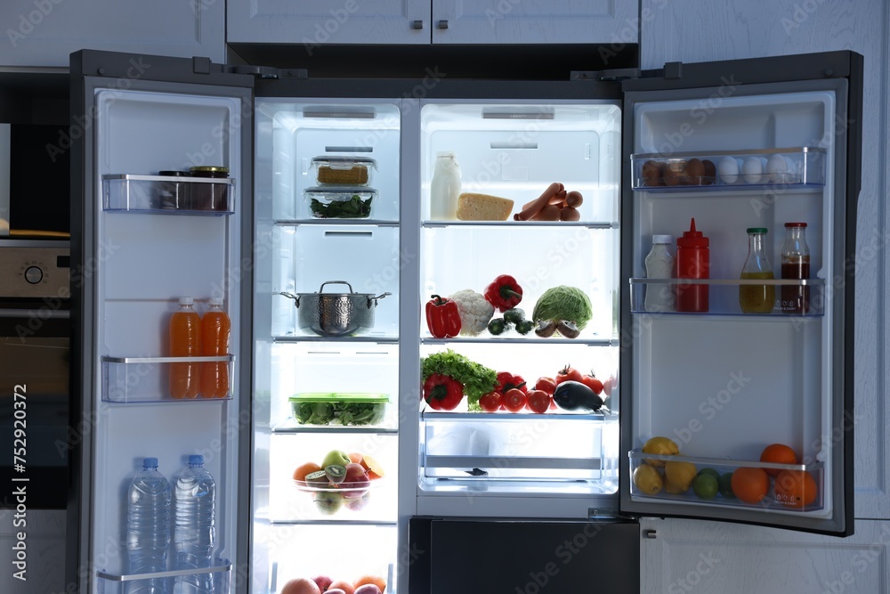 Open refrigerator full of different products in kitchen Open refrigerator full of different products in kitchen