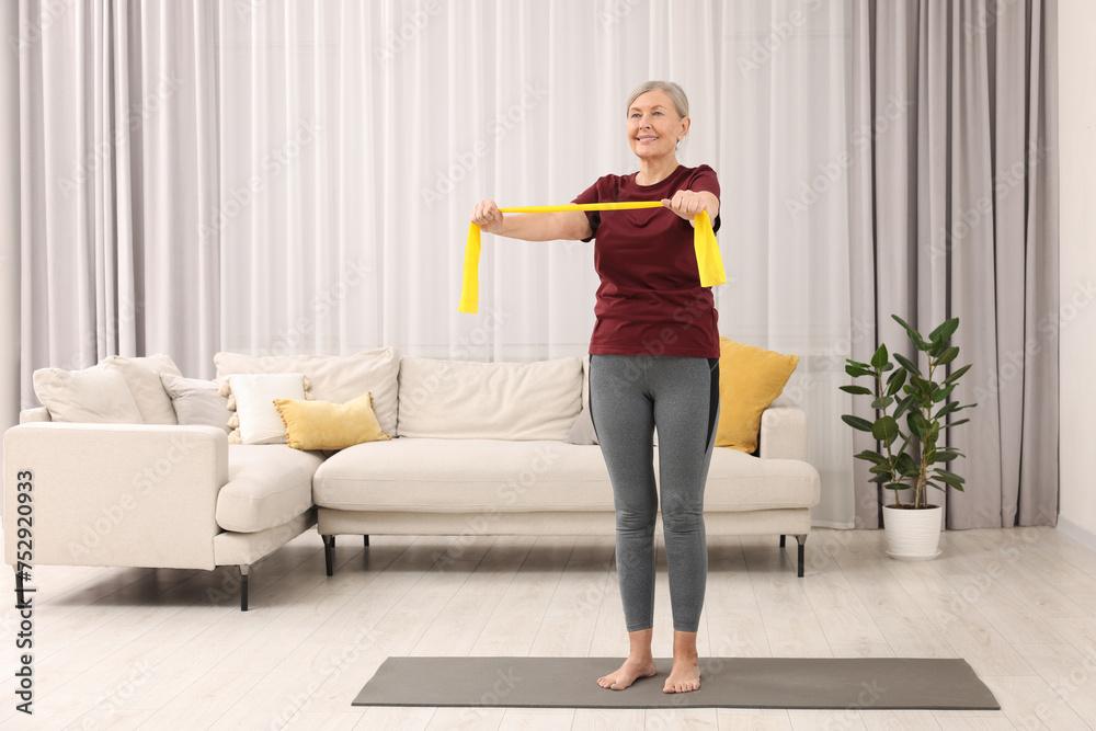 Senior woman doing exercise with fitness elastic band on mat at home Senior woman doing exercise with fitness elastic band on mat at home