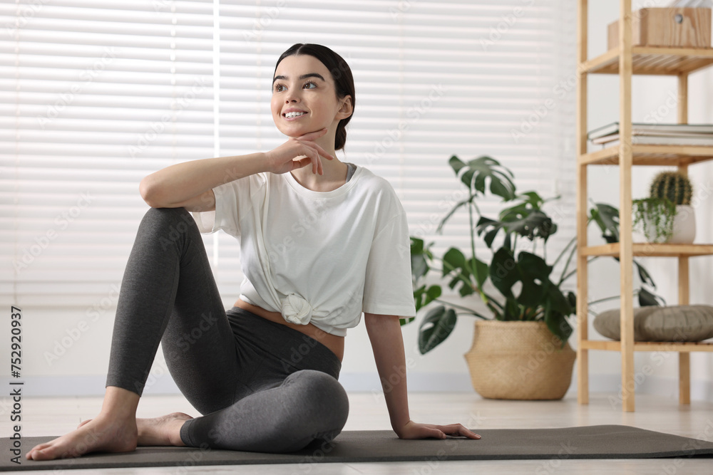 Beautiful girl sitting on yoga mat in studio Beautiful girl sitting on yoga mat in studio