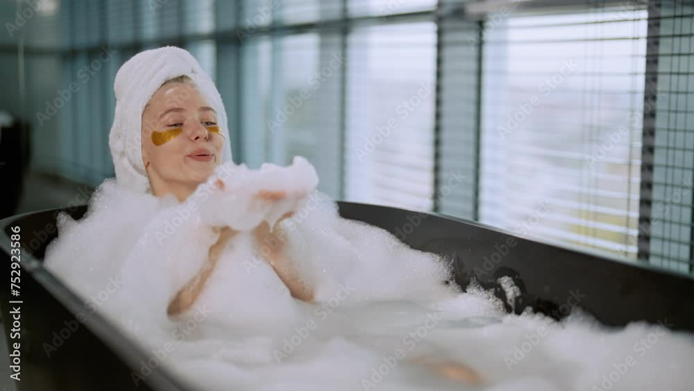 Girl enjoying taking bath with foam. Smiling positive woman with eye