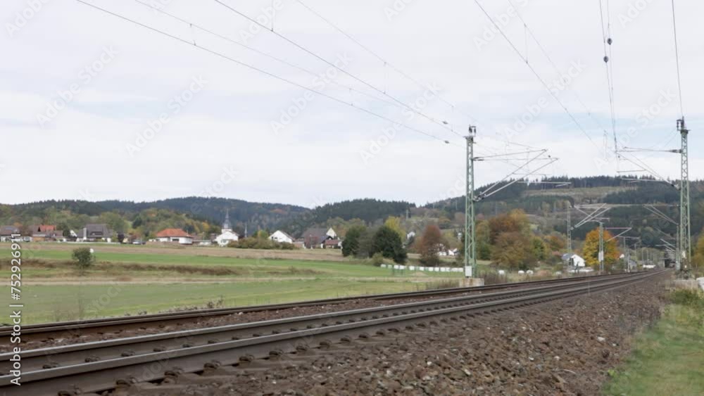 Red Deutsche Bahn train approaching on tracks through a rural landscape with houses and church in the background, daytime Red Deutsche Bahn train approaching on tracks through a rural landscape with houses and church in the background, daytime