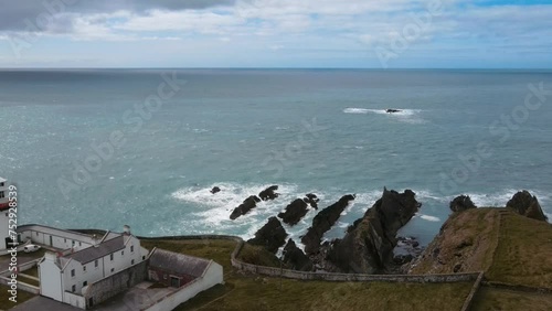 Wallpaper Mural drone flying along a white lighthouse over rocks in the ocean, Ireland Torontodigital.ca