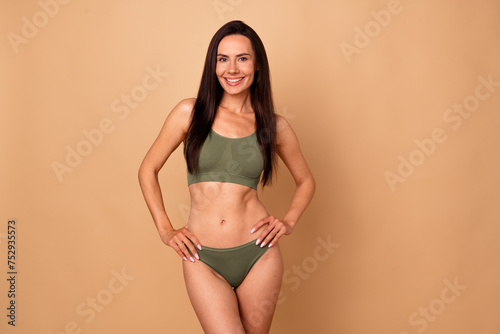 Photo portrait of lovely young lady hands waist posing model no filter dressed stylish khaki underwear isolated on beige color background © deagreez