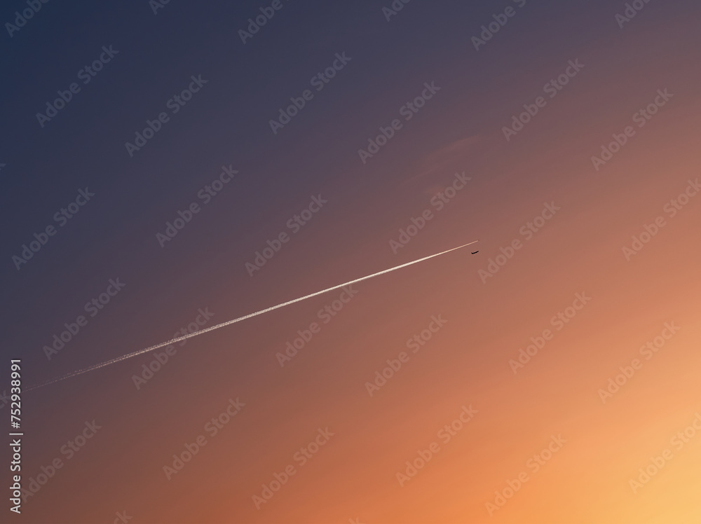 Jet plain flying into the sunset diagonal exhaust trace