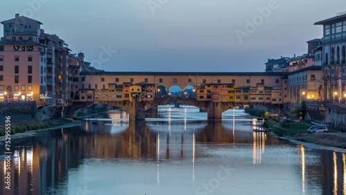 River Arno and famous bridge Ponte Vecchio day to night transition timelapse from Ponte alle Grazie in Florence after sunset, Tuscany, Italy. Reflection on the river with evening illumination photo