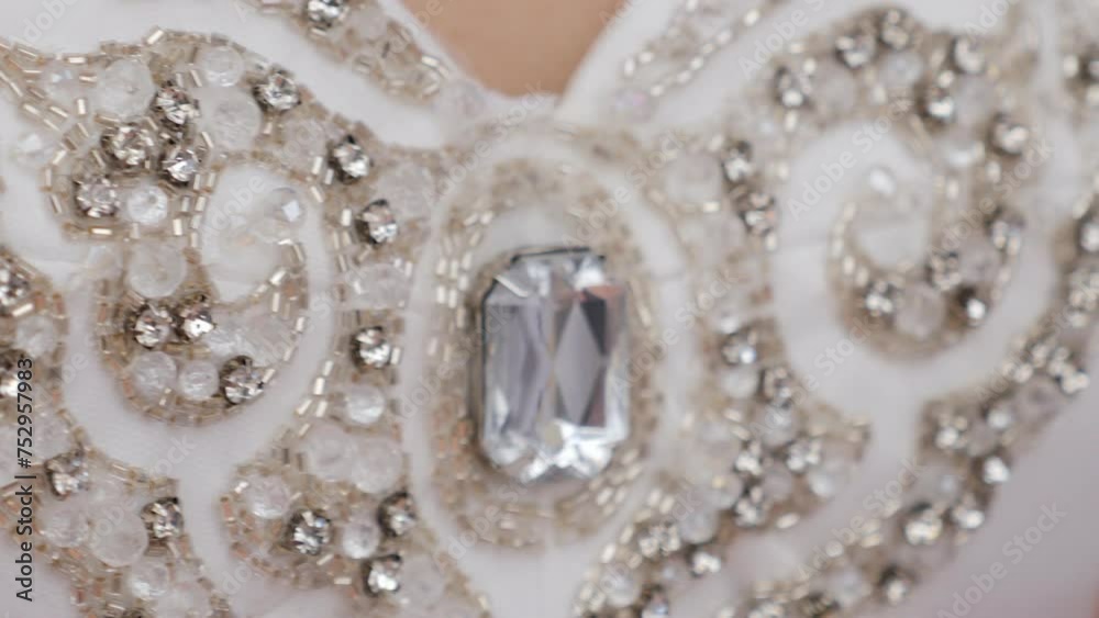 A close-up of the bride's dress decorated with stones, a luxurious wedding dress. Wedding fashion.