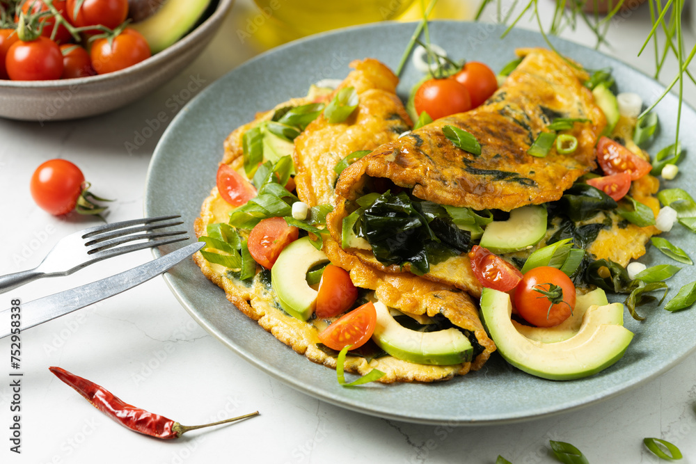 Pancakes with seaweed. Served on a plate with avocado and tomatoes.