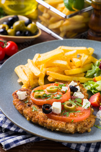 Breaded pork chop in tomatoes. Served with olives and feta cheese.