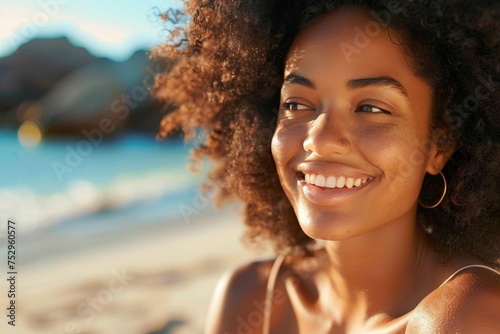 A close-up portrait of a cheerful woman with curly hair enjoying a beautiful sunset on the beach