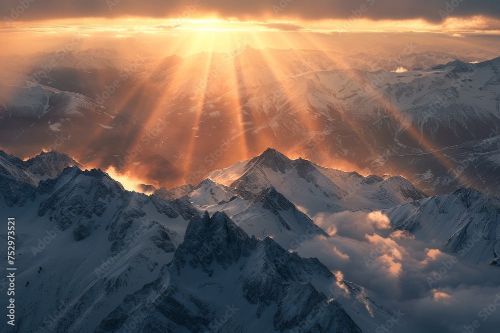 Snow capped mountain peaks with sunlight piercing through clouds