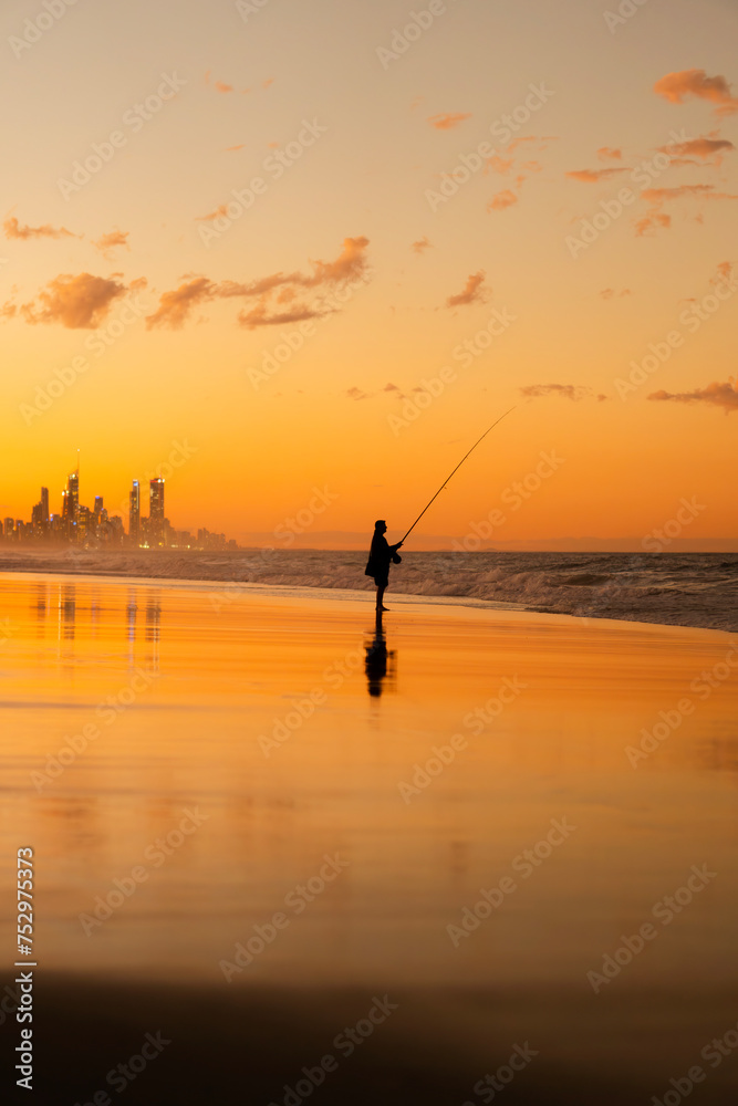 Landscape of an Australian beach during sunset with the silhouette of a fisherman. Burleigh Heads, Gold Coast