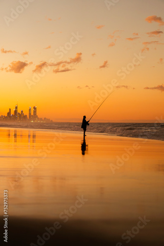 Landscape of an Australian beach during sunset with the silhouette of a fisherman. Burleigh Heads, Gold Coast