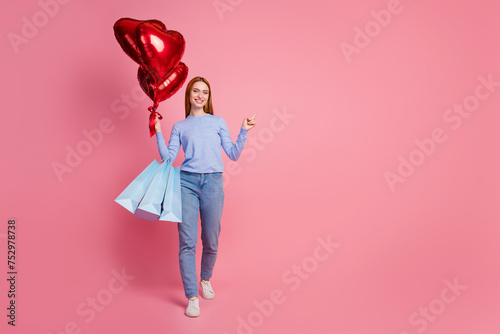 Full body photo of cheerful woman hold bubbles new clothes in bags indicating at proposition empty space isolated on pink color background