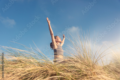 Sporty woman with her arms raised and face to the sun, photo