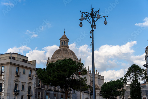 A tall building with a dome on top stands in front of a street light