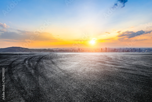 Empty asphalt road and city skyline background at sunset © zhao dongfang