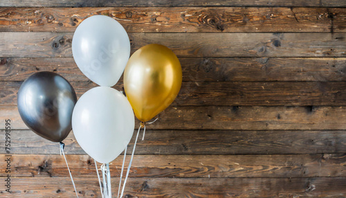 Festive gold, silver and white balloons against wooden wall background with copy space for text