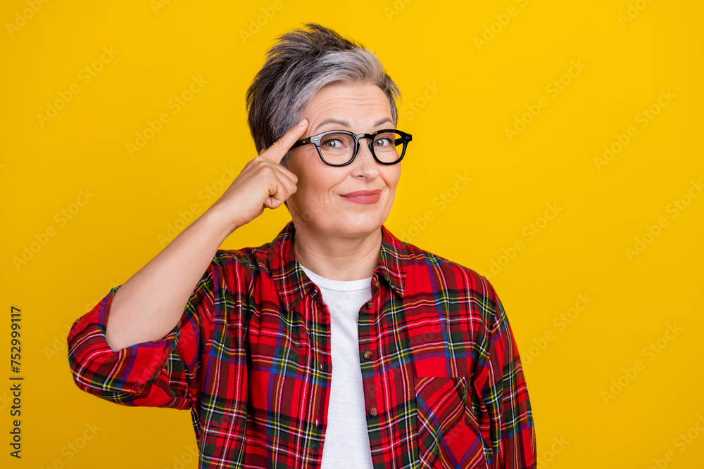 Portrait of creative intelligent positive person finger touch temple think empty space isolated on yellow color background Portrait of creative intelligent positive person finger touch temple think empty space isolated on yellow color background