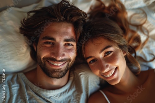 Loving couple enjoying a cozy morning in bed, embracing each other with smiles on their faces. © tonstock