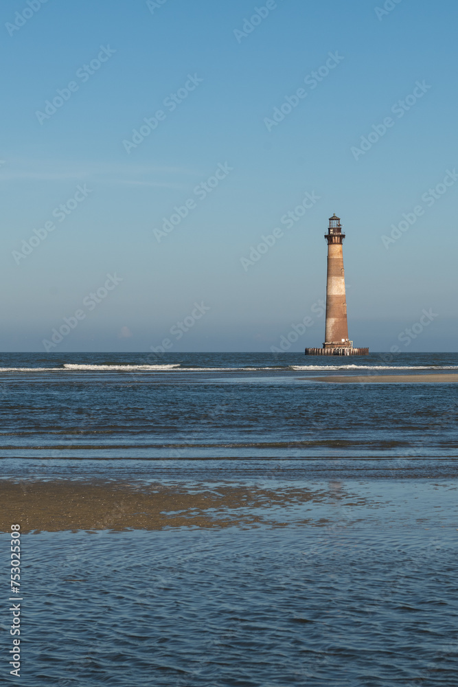 Naklejka premium Morris Island Lighthouse from the shoreline of Folly Beach near Charleston, South Carolina.